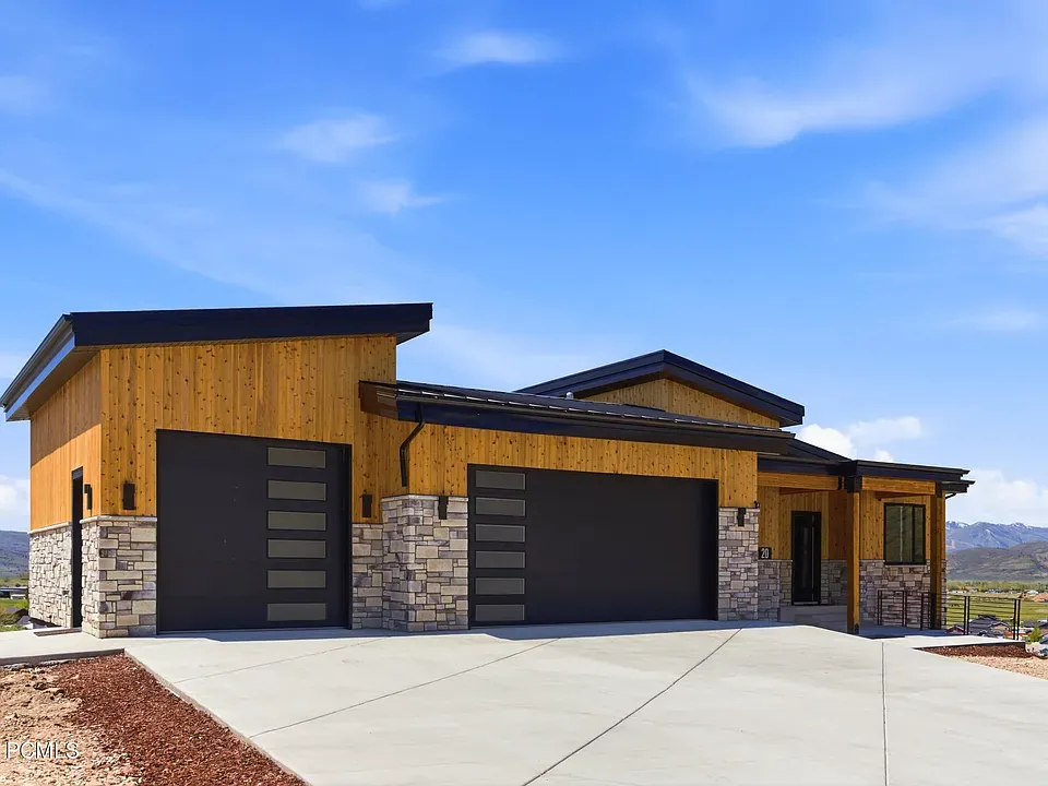 Modern cedar and stone home with dual garages under blue Utah sky
