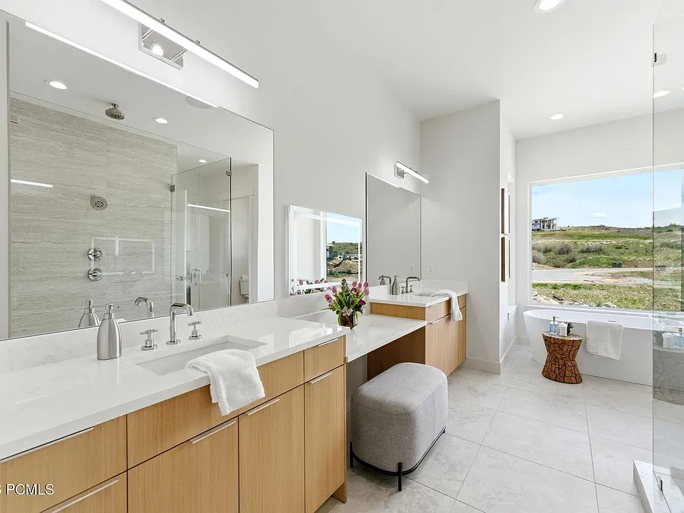 Primary bath with dual vanities, soaking tub, and mountain window